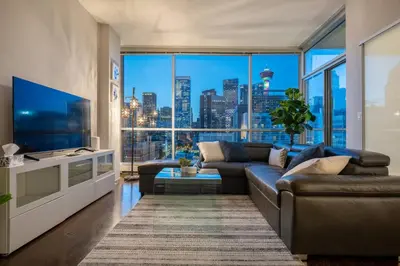 a living room with a couch and a large window at Downtown Chic Retreat | Elegant + Free Parking in Calgary