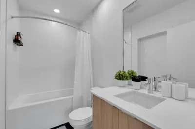 a bathroom with a sink and a toilet and a mirror at Stylish Beltline 1BR w/ Parking in Calgary