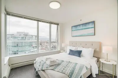 a bedroom with a bed and a large window at Executive Unit with Spectacular Views in Vancouver