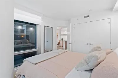 a white bedroom with a bed with a large window at Executive Downtown Suite with Great City Views in Vancouver