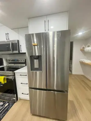 a stainless steel refrigerator in a kitchen with white cabinets at Your Cozy Happy Place in Calgary