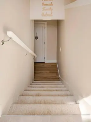 a staircase leading up to a white room with a door at Victoria's Family Oceanside Retreat, brand new 2br basement in Colwood