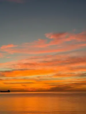 a sunset over the ocean with a boat in the water at Victoria's Family Oceanside Retreat, brand new 2br basement in Colwood