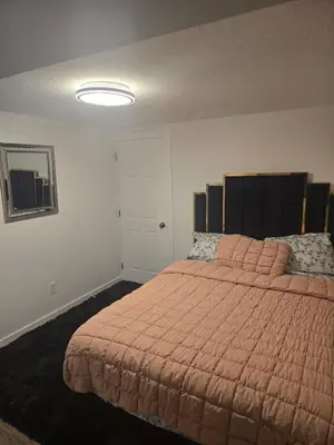 a bedroom with a large bed with a orange comforter at Cozy 2-Bedroom Suite 5 Minutes Walk to Chestermere Lake in Chestermere