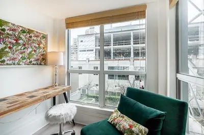 a living room with a green chair and a window at Trendy Loft in Downtown in Vancouver