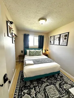 a bedroom with a bed with blue curtains and a rug at The house Londonderry mall in Edmonton
