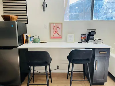 a kitchen with two bar stools and a counter at The Chimney Studio with Gigantic Outdoor Fireplace in Calgary