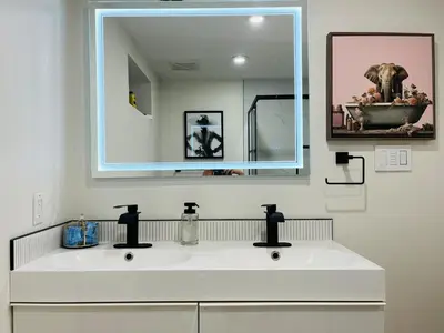 a bathroom with a white sink with a large mirror at The Chimney Studio with Gigantic Outdoor Fireplace in Calgary