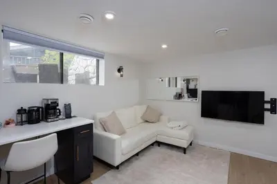 a white living room with a couch and a tv at The Chimney Studio with Gigantic Outdoor Fireplace in Calgary