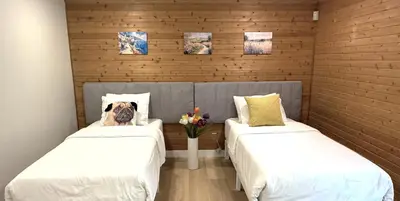 a room with two beds with a dog sitting between them at Vancouver Lake City Way Guesthouse 10 min to SkyTrain in Burnaby