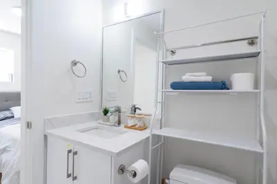 a white bathroom with a sink and a mirror at Quiet, cozy 2BR1BA private entry suite near Skytrain in Vancouver
