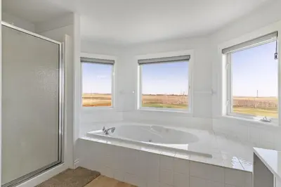 a white bathroom with a tub and two windows at Acreage, 5 bdrm, King Bed, AC, Wood Fireplace, Rural in Balzac