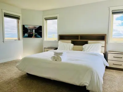 a bedroom with a large white bed with two towels on it at Acreage, 5 bdrm, King Bed, AC, Wood Fireplace, Rural in Balzac