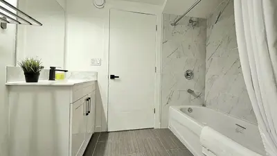 a white bathroom with a tub and a sink at Quiet Family Friendly, 4 min UofC and University District Shops, 9 min DT in Calgary