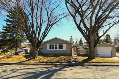 a house with two trees in front of a street at Quiet Family Friendly, 4 min UofC and University District Shops, 9 min DT in Calgary