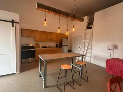 a kitchen with a table and two stools and a ladder at Mezzanine Loft Above the Barn in Whitehorse