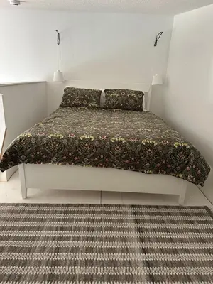 a bedroom with a bed with a blanket and a rug at Mezzanine Loft Above the Barn in Whitehorse