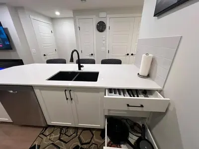 a white kitchen with a sink and a counter at Deluxe 2-Bedroom Getaway Near Calgary Airport Sleeps Up to 6 in Calgary