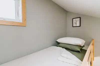 a small bedroom with a bed and a window at Roamer's Nook in Nordegg
