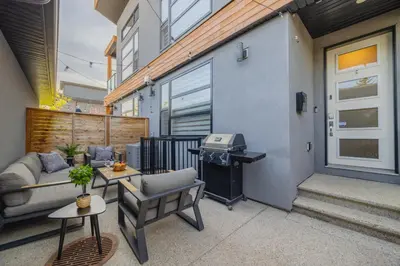 a patio with a couch and a grill next to a building at Home Theater with AC, Dual Master Suites, BBQ in Calgary