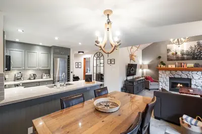 a kitchen and dining room with a table and a fireplace at Arrowhead Point 2 by Outpost Whistler in Whistler