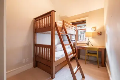 a bunk bed in a room with a desk and a bunk bed at Fitzsimmons Walk 10 by Outpost Whistler in Whistler