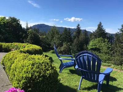 two blue chairs sitting in the grass near some bushes at Belle Maison Auprès De La Mer in Sidney