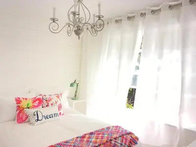 a bedroom with a bed with a chandelier and a window at Belle Maison Auprès De La Mer in Sidney