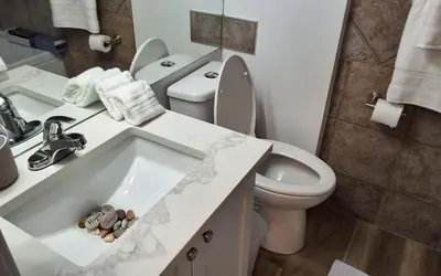 a white bathroom with a toilet and a sink at Modern 1br Apt, Up to 4 people, Steps to 17th Ave, Downtown & Stampede in Calgary