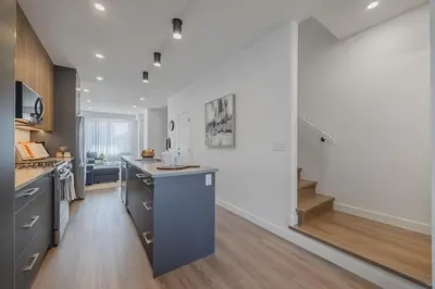 a kitchen with white walls and wooden floors at Upper and Lower, Great for Large Families, Fenced Yard in Calgary