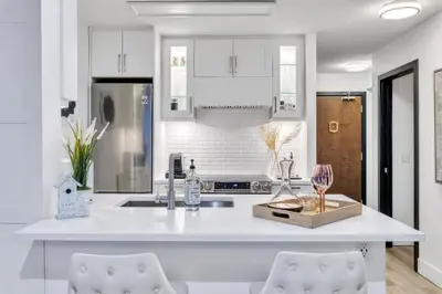 a kitchen with white cabinets and a counter with two chairs at Modern 2BR 2BA Condo in Heart of Vancouver in Vancouver