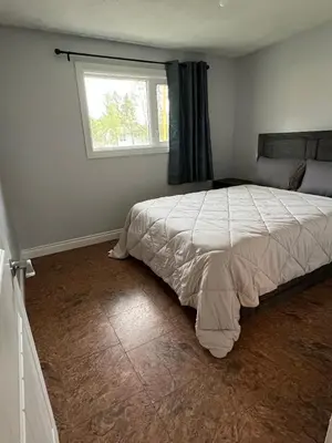 a bedroom with a large bed with a window at Cozy Riverdale Home in Whitehorse
