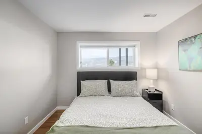 a white bedroom with a bed and a window at Knox Mountain Vista 2 Bdrm Suite in Kelowna