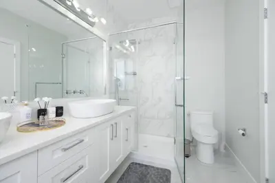 a white bathroom with a sink and a shower at Modern 3BR Near Langley Events Centre & EV charger in Langley