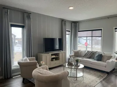 a living room with a couch and chairs and a tv at Le Reve Show Home 3BD, AC, sleep 9 , Beaumont in Nisku