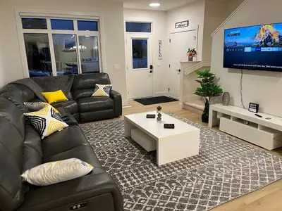 a living room with a black leather couch and a tv at Full Luxury home 4 BD ,AC,sleep 14,BBQ, 2V Garage in Edmonton