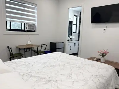 a bedroom with a bed and a table and a television at Bird Nest Suites in Surrey