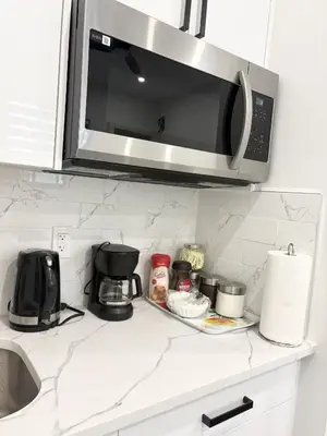 a kitchen counter with a microwave above a sink at Bird Nest Suites in Surrey