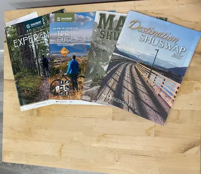 three magazines sitting on top of a wooden table at Blind Bay Chalet 2 Bedroom Private Suite in Blind Bay