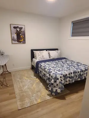 a bedroom with a bed with a blue and white blanket at Spacious 2 Bedroom Suite in Gorman, Edmonton, Canada in Edmonton