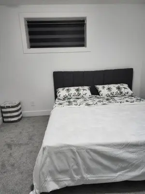 a bedroom with a bed with white sheets and pillows at Spacious 2 Bedroom Suite in Edmonton, Canada in Edmonton