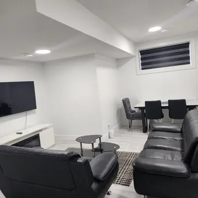 a living room with black leather furniture and a tv at Spacious 2 Bedroom Suite in Edmonton, Canada in Edmonton