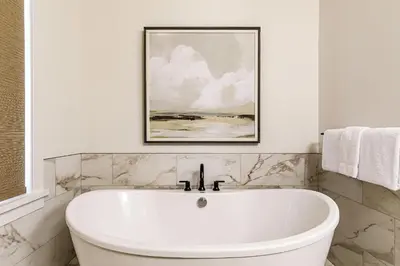 a white bath tub in a bathroom with a painting at Creekside Elegance at Timberstone in Canmore