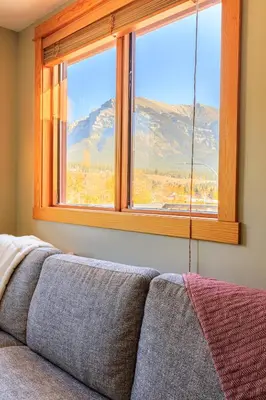a living room with a couch and a window at Boardwalk Bliss - Top Floor Downtown Condo in Canmore