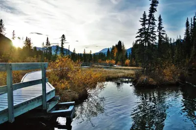 a bridge over a river with a boat in the water at Boardwalk Bliss - Top Floor Downtown Condo in Canmore