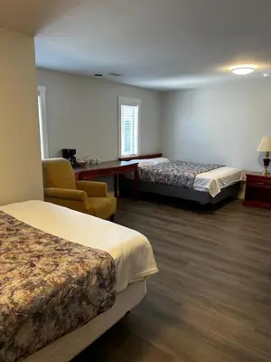a hotel room with two beds and a chair at Lakecity Inn in Penticton
