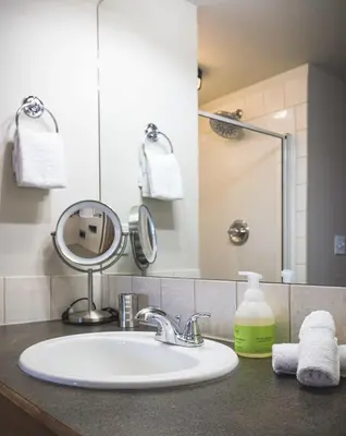 a bathroom counter with a sink and a mirror at Mountainside - Stunning Views Downtown Location in Canmore