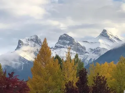 a mountain range with trees and snow covered mountains at Mountainside - Stunning Views Downtown Location in Canmore