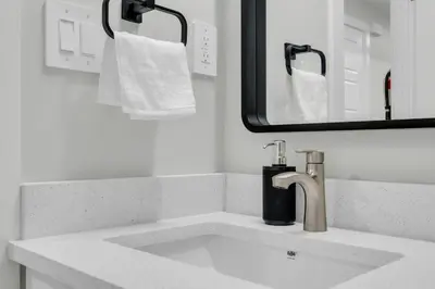 a bathroom with a sink and a mirror and towels at Cozy Luxe Suite in Calgary