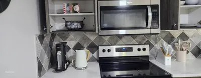 a kitchen with a microwave and a stove top oven at The Vaulted Oasis 2-bedroom with a Garden in Airdrie
